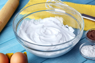 Whipped egg whites for cream on color wooden table, closeup