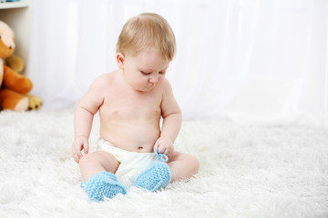 Cute baby boy on carpet, on light background