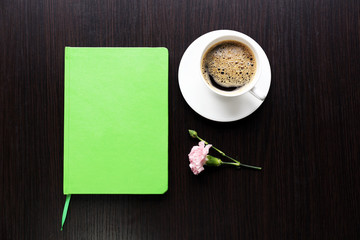 Cup of coffee with notebook and fresh flower