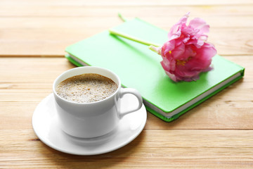 Cup of coffee with notebook and fresh flower