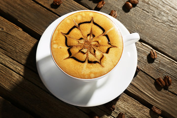 Cup of coffee latte art with grains on wooden background