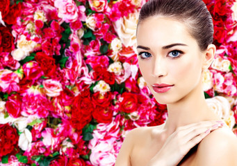 Beautiful woman on a floral background with red and white roses