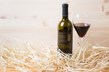 Bottle and glass of red wine with cork in straw