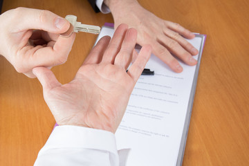 Cropped image of man signing contract with keys on it