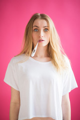 Blonde Frau mit Fieberthermometer schaut erschrocken