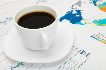 Coffee cup over world map and some market charts