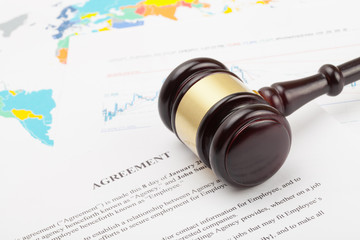 Wooden judge's gavel over agreement documents and world map