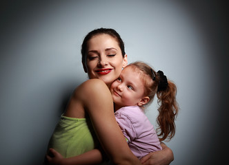 Happy smiling mother hugging her cute girl with love