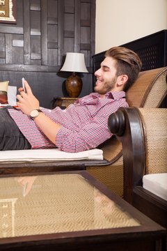 Junger Mann mit Smartphone im Hotelbett