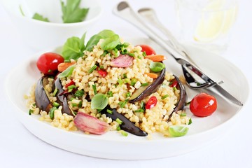 Bulgur salad with vegetables and herbs on a white background.