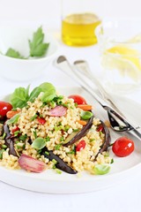 Bulgur salad with vegetables and herbs on a white background.