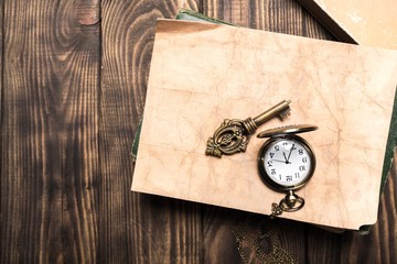 Abstract. Vintage pocket watch, old book and a brass key on a
