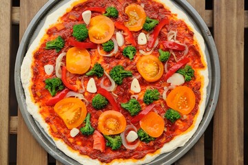 Raw round pizza with yellow cherry tomatoes, onion, garlic and b