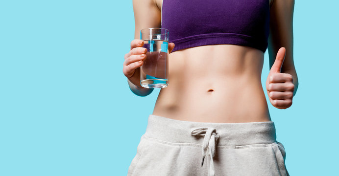 Woman showing her abs with water glass