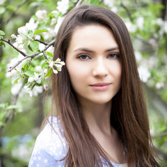 Beautiful woman standing near blooming trees in spring garden