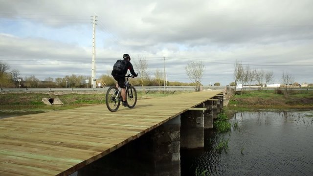 mountain bicycle riding on a wooden bridge on a cloudy day