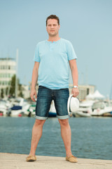Fashion portrait of handsome man on pier against yachts