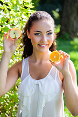 Beautiful close-up portrait of young woman with orange and apple