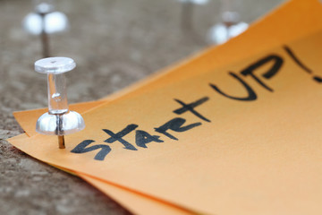 close up on pin and strat up word on sticky note with cork board