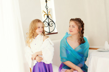 Fototapeta premium Playful well-dressed sisters looking at each other