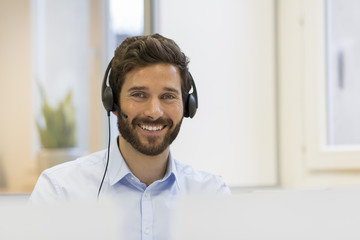 Happy Businessman in the office on the phone, headset, Skype