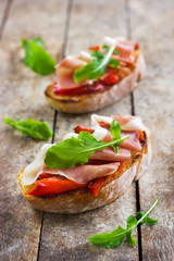 bruschetta with roasted peppers, prosciutto and arugula