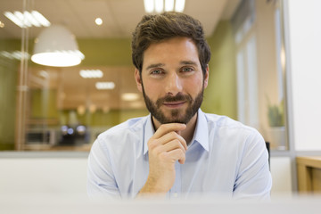 Portrait of handsome bearded man in office. looking camera