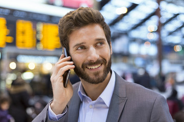 Cheerful man on the mobile phone in hall station