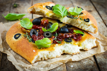 piece of Italian focaccia bread with black olives, dried tomatoe