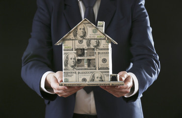 Model of house made of money in male hand, close up