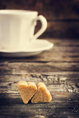 cup of coffe and brown cane sugar with shape of heart on old woo