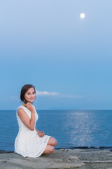 Portrait of pretty young girl at the beach with moon shining
