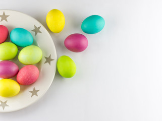 Plate full of colorful painted eggs on white background