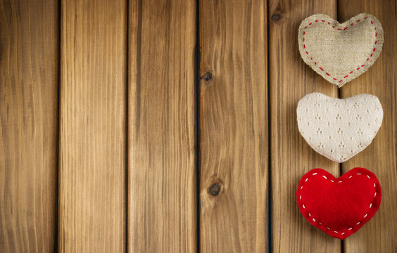 Row of different soft hearts on wooden background