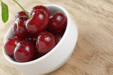 ripe cherry berries in white bowl on wood table