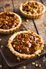 Tart with nuts and caramel on a rustic  background
