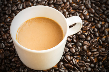 Hot latte coffee cup on coffee beans background.