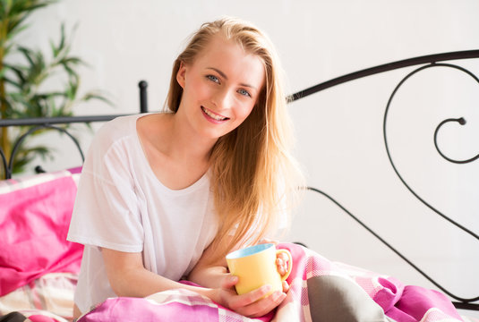Blondes Mädchen geniesst einen Kaffee im Bett