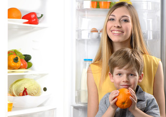 Young mother and her little son near open fridge