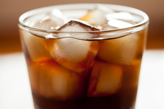 Cola sweet drink with ice cubes and bubbles in glass