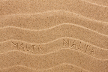 Malta inscription on the wavy sand