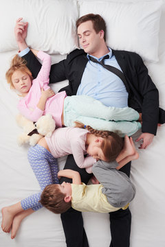 Top view of chidren sleeping all over father