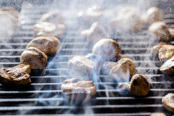 Champignon mushrooms grilled on BBQ with steam and drops of