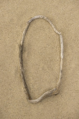 Fototapeta na wymiar Alphabet Buchstabe O aus Treibholz auf Sand