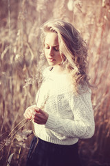 Portrait of pensive beautiful young blonde girl in a field