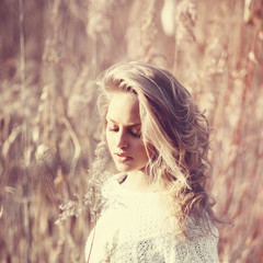 Portrait of pensive beautiful blonde girl in a field