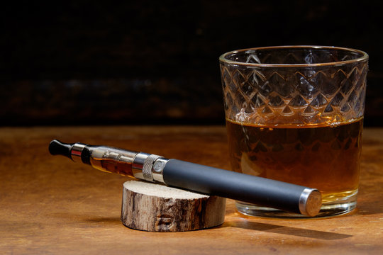 vintage still life with e-cigarette and a glass of bourbon