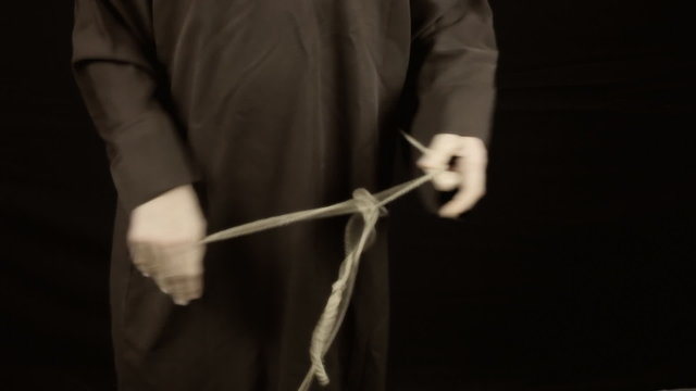 Friar dressing tying knot in habit sackcloth