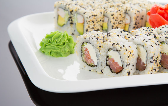 Japanese tasty sushi set on a white plate over black background