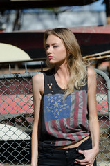 Blonde women is leaning against a fence